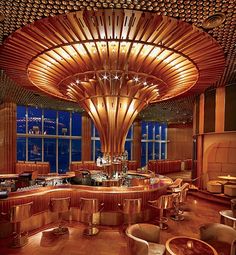 a restaurant with wooden tables and chairs in front of large windows overlooking the city at night