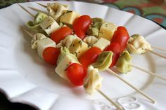 a white plate topped with kebabs and tomatoes