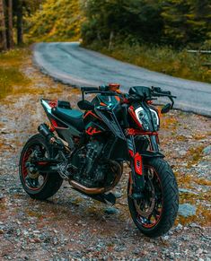 a black and red motorcycle parked on the side of a road next to some trees