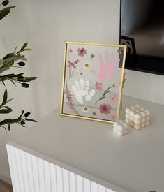 a white table with a painting and some flowers on it