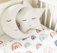 two pillows that are on top of a crib in a room with white walls