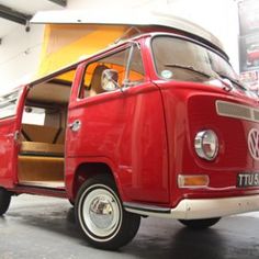 an old vw bus is parked in a garage with its doors open and the door ajar