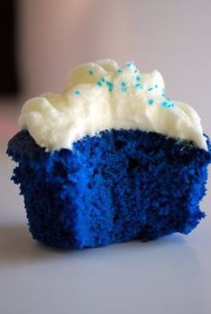 a blue cupcake with white frosting and sprinkles on it's side