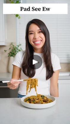 a woman is eating spaghetti with chopsticks in her hand and the caption reads pad see ew