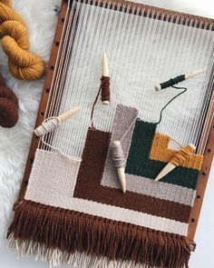 two yarns are laying next to each other on a white surface with a brown and yellow weaving machine