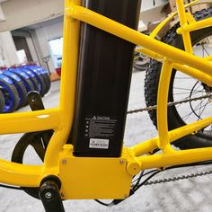 a close up of a yellow bicycle in a building with other bikes and bicycles behind it