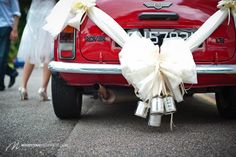 the back end of a red car with bells tied to it