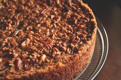 a cake with pecans on top sitting on a wire rack in front of a window