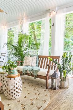 the porch is decorated with potted plants and wicker furniture, along with other outdoor decor