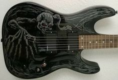 a black electric guitar with skulls on it's body and strings hanging from the wall