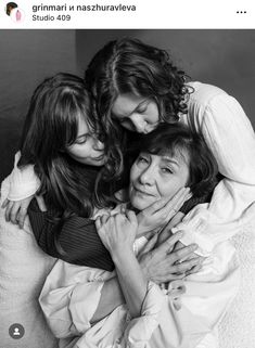 three women hugging each other while sitting on a bed with their arms around one another