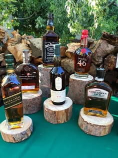 several different types of liquor sitting on top of wooden stumps in front of some trees