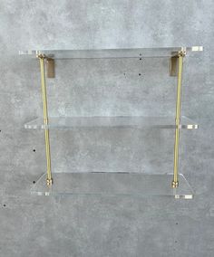 three glass shelves with gold handles on each shelf, one is empty and the other has two