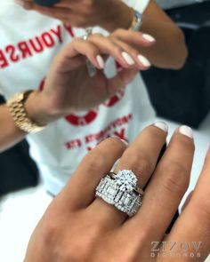 a woman is holding her engagement ring while looking at her cell phone in front of her