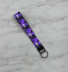 WHAT'S YOUR FAVORITE SCARY MOVIE?!?! Features a black background with purple planchettes, Ghost in a black robe with a purple background, and "CALL ME" on the Ouija Planchettes. The perfect fun and spooky gift! Lanyard is made out of 100% polyester webbing and is 3/4" wide, image is sublimated onto the webbing strip. Style 1 Lanyard is held together using rivet, a D-ring with lobster clasp closure to hook to your keys. Style 2 Lanyard is held together with a flat clasp with a keyring attached to it. Opening for your hand is approximately 4"tall. From top to clasp the lanyard is approximately 6" tall. All items are handmade and measurements are approximate. Inside of lanyard may be black or white,  depending on what is available from suppliers. --** Get a matching phone grip here:  --** Get Trendy Black Keychains, Trendy Black Keychain With Key Leash, Halloween Lanyard, Black Wristlet With Key Leash For Everyday Use, Black Keychain With Key Leash For Personal Use, Black Lanyard With Key Leash For Personal Use, Beetlejuice Keychain, Adjustable Black Lanyards With Key Clip, Horror Keychain