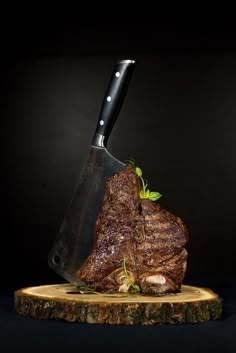 a piece of meat with a knife stuck in it on a wooden board next to a black background