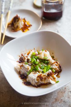 two white plates with food on them and chopsticks next to one plate full of food