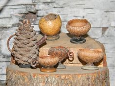 an assortment of pine cones and vases on top of a tree stump with a brick wall in the background