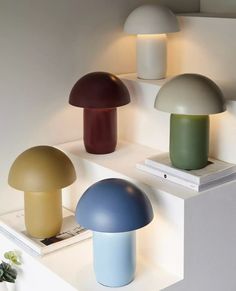 three different colored lamps sitting on top of a shelf