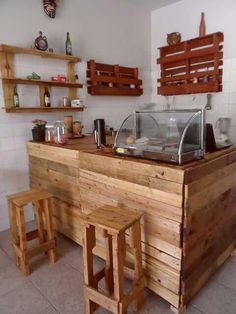 a wooden counter sitting inside of a kitchen next to two stools on the floor