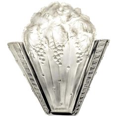 an art deco glass vase with flowers and leaves on the top, set against a white background