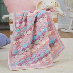 a crocheted blanket sitting on top of a chair next to a stuffed animal