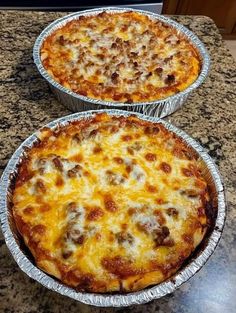 two pizza pies sitting on top of a counter next to each other in pans