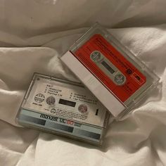 two old fashioned cassettes sitting on top of a white sheet covered bed next to each other