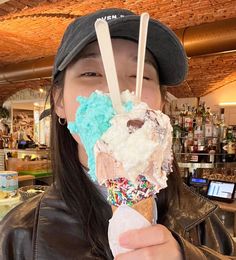 a woman holding up an ice cream cone with sprinkles and toppings