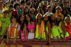 a group of young people standing next to each other in front of a large crowd