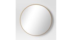 a round mirror on the wall with gold trimmings and a white back ground