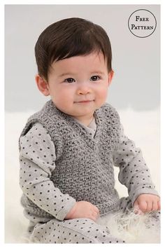 a baby sitting on the floor wearing a gray sweater and white pants with polka dots