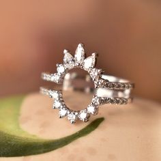 a diamond ring sitting on top of a green leaf