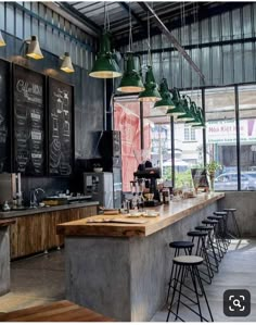 a restaurant with chalkboard menus hanging from the ceiling and bar stools at the counter