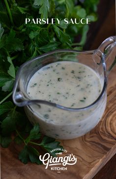 parsley sauce in a glass pitcher on a cutting board with parsley around it