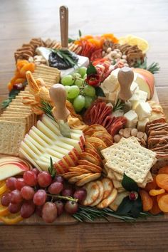 a wooden table topped with lots of different types of cheese and crackers