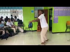 a woman standing in front of a classroom full of people and holding a wii controller