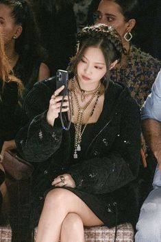 a woman sitting in front of a crowd holding a cell phone