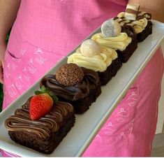 a person holding a long white plate with chocolate cake and strawberries on it in the shape of a train