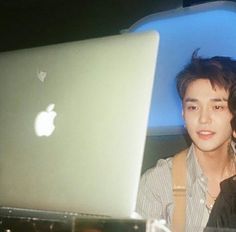 two people sitting next to each other in front of an apple laptop