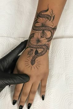 a woman's hand with a tattoo on it and a snake wrapped around the wrist