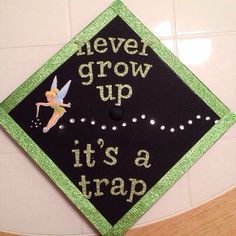 a black and green graduation cap that says never grow up it's a trap