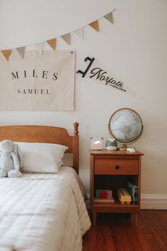 a bed room with a neatly made bed and a stuffed animal on the side table