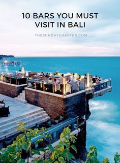 an outdoor dining area overlooking the ocean at dusk with tables and umbrellas on top