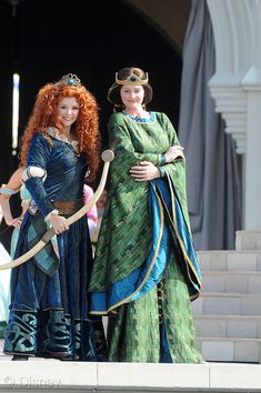 two women dressed up as disney princesses standing on steps with swords in their hands