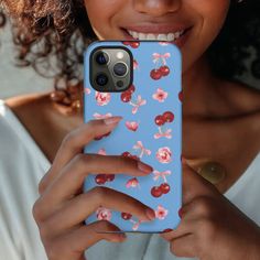 a woman is holding up her phone case with cherries on it and smiling at the camera