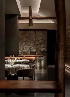 an empty restaurant with tables and chairs set for two, in the middle of a room that has stone walls