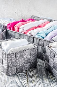 an assortment of folded clothes sitting on top of a wooden table