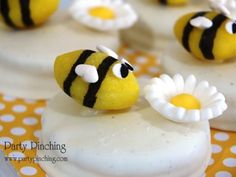 some yellow and black decorated cookies with white flowers on them are sitting on a polka dot tablecloth