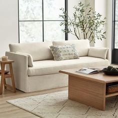 a living room with a white couch and wooden coffee table in front of large windows